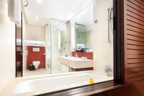 e bagno con vasca, servizi igienici e lavandino. di Howard Johnson Parkland Hotel Dalian a Dalian