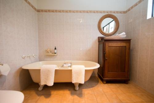 a bathroom with a bath tub and a mirror at Boathouse - Birks River Retreat in Goolwa