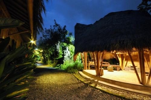 a house with a thatched roof and a pathway at Ubud Art Resort in Ubud