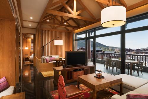 a living room with a television and a balcony at Jinmao Pureal Mountain Liiang in Lijiang