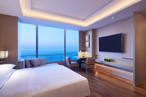 徐州市にあるHyatt Regency Xuzhouの大型ベッド1台、薄型テレビが備わるホテルルームです。