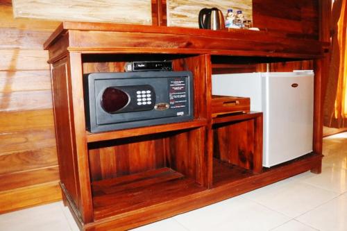a microwave oven in a wooden cabinet next to a refrigerator at Pemedal Beach Resort in Nusa Lembongan