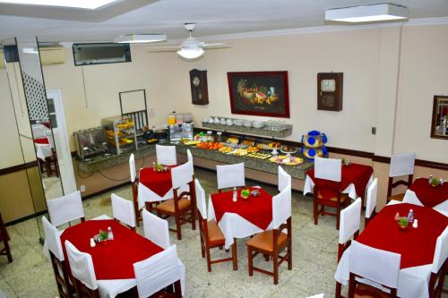 uma sala de jantar com mesas e cadeiras vermelhas e brancas em Hotel Comendador em Três Rios