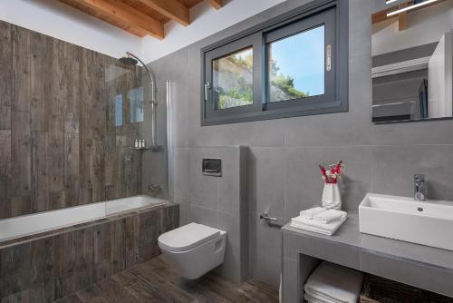 y baño con aseo, lavabo y bañera. en Kathisma Bay Villas - Luxury Villas- Villa Oceanos, en Kalamitsi