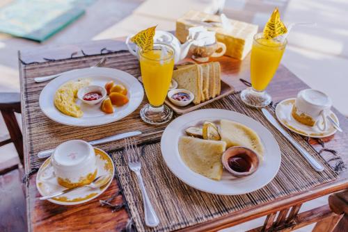 a wooden table with plates of breakfast foods and drinks at Dream Beach Inn in Nusa Lembongan