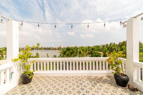 a balcony with potted plants and a view of the water at Sunny Riverside Homestay in Hoi An