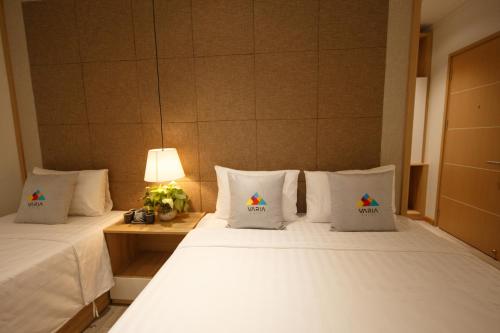 a bedroom with two beds and a table with a lamp at VARIA Hotel Phu Quoc in Phu Quoc