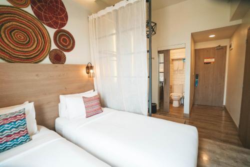 two white beds in a room with a bathroom at Lub d Manila Makati - Central Makati, Near Nightlife in Manila