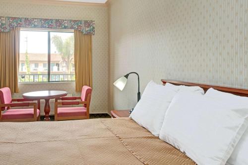 a bedroom with a bed and a table and a window at Travelodge by Wyndham Lynwood in Lynwood