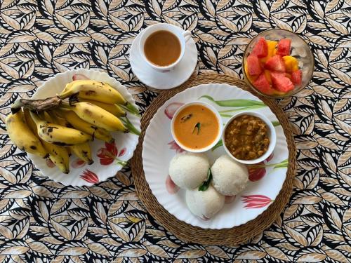 two plates of food with fruit and a cup of coffee at Neela Waters - Beach Home in Alleppey