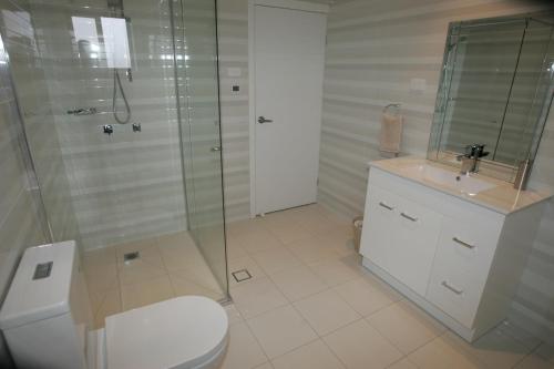a bathroom with a shower and a toilet and a sink at Kindred Lodge Apartments in Leeton