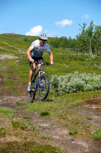 a man riding a bike down a grassy hill at STF Hemavans Fjällcenter in Hemavan