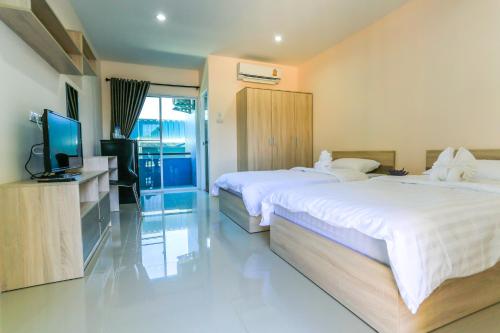a hotel room with two beds and a flat screen tv at Tempo Plus Apartment in Mae Sot