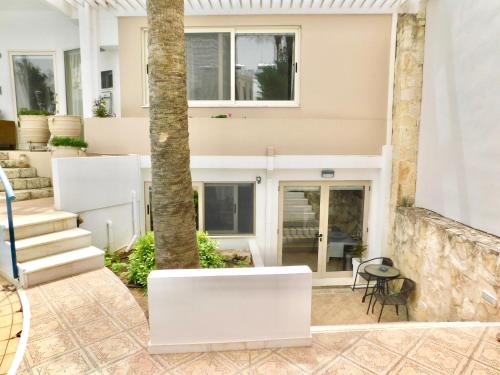 a white house with a palm tree and stairs at Elizabeth Suites in Kato Daratso