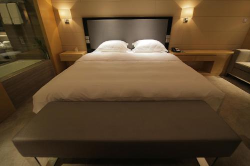 a bed with white sheets and pillows in a room at Huangyan Yaoda Hotel in Taizhou