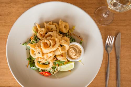 a white plate of food with a salad with calamari at Riverfront Motel & Restaurant in Hobart
