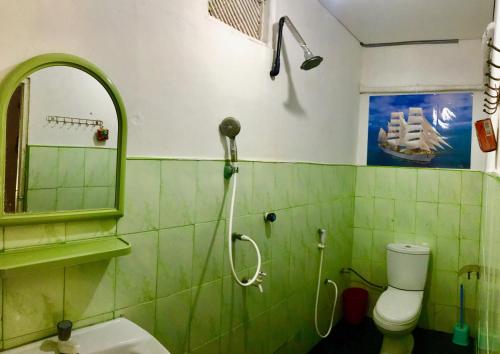 a green tiled bathroom with a shower and a toilet at Star Rest Surf Camp Arugambay in Arugam Bay