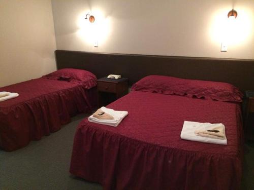 2 Betten in einem Hotelzimmer mit Handtüchern darauf in der Unterkunft Feilding Hotel in Feilding