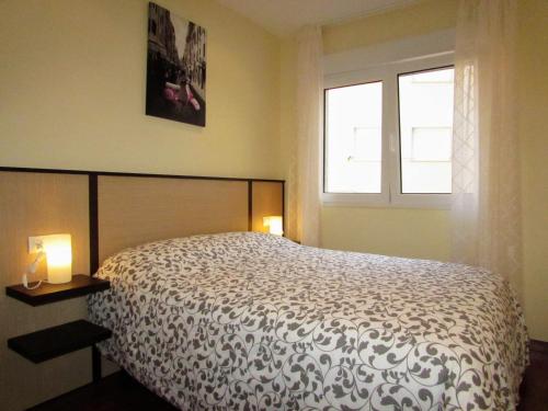 a bedroom with a bed and two lamps and a window at Apartamento en centro de Fisterra in Fisterra