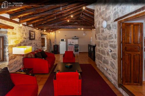 una sala de estar con muebles de color rojo y una pared de piedra. en Alojamiento rural "El Torreón", en Sabiote