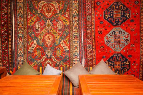 a room with two beds and a wall with a rug at CHALET DILIJAN Hotel & Restauarant in Dilijan