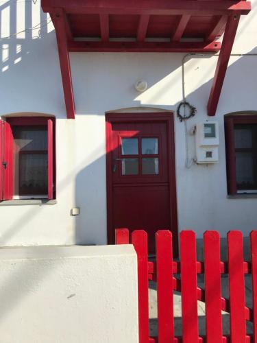 a red fence in front of a house with a red door at Verantaki in Kithnos