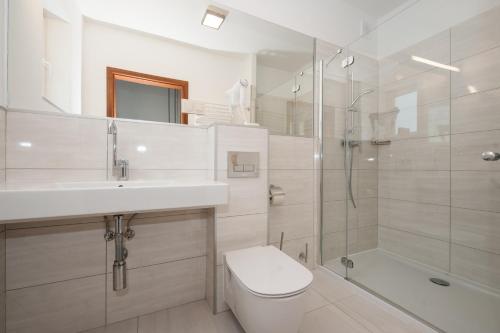 a bathroom with a toilet and a sink and a shower at Apartamenty przy Latarni in Niechorze
