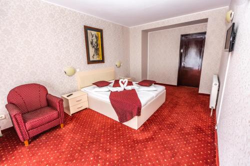 a hotel room with a bed and a chair at Hotel Miraj - Restaurant & Sauna & Biliard in Poiana Brasov