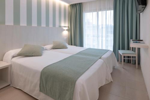 een hotelkamer met een groot wit bed en een raam bij Mercè in Pineda de Mar