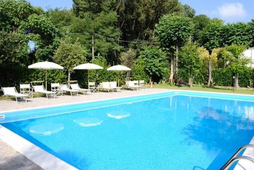 une grande piscine bleue avec des chaises et des parasols dans l'établissement Rta la Pergola, à Marina di Massa