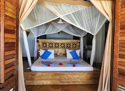 a bed with blue and white pillows and a canopy at SeVi Boutique Hotel in Matemwe