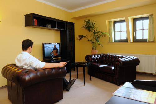 un hombre sentado en una silla viendo una televisión en Braugasthaus, en Naumburg