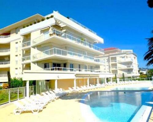 um grande edifício com piscina e cadeiras em Appartement Cannes vue mer 4 pers avec piscines em Cannes