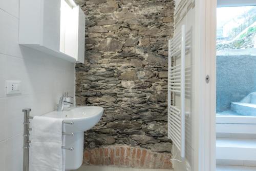 a bathroom with a sink and a stone wall at Il Giardino di Riomaggiore Suite in Riomaggiore