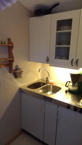 a kitchen with a sink and white cabinets at Kvarngården Natur Resort in Byxelkrok