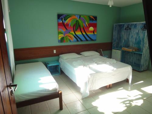 a bedroom with two beds and a painting on the wall at Pousada Maresia in Itacaré