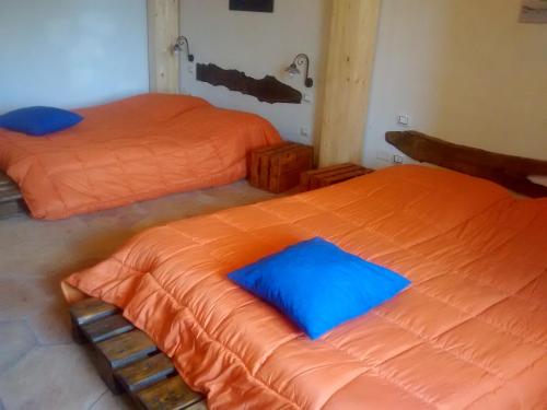 two beds with orange sheets in a room at Agriturismo La Caraffara sull' Etna in Puntalazzo