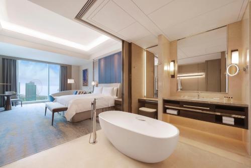 ein Badezimmer mit einer Badewanne und ein Schlafzimmer mit einem Bett in der Unterkunft Shangri-La Yuanqu, Suzhou in Suzhou