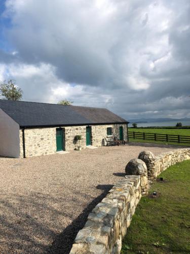 a stone building with a stone wall next to a field at Oakwell holiday village in Ramelton