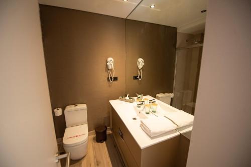 a bathroom with a sink and a toilet and a mirror at Hotel Diufain in Conil de la Frontera