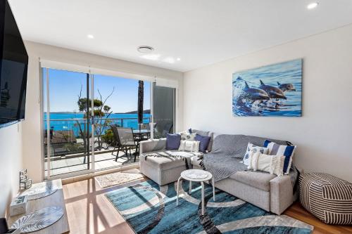 a living room with a couch and a tv at The Shoal Apartments, Unit 504/4-8 Bullecourt Street in Shoal Bay