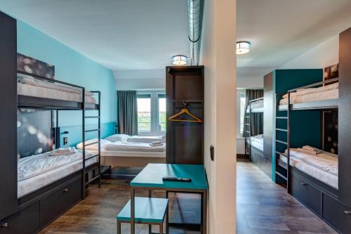 ミュンヘンにあるマイニンガー ホテル ミュンヘン オリンピアパークの二段ベッド3組とテーブルが備わる客室です。
