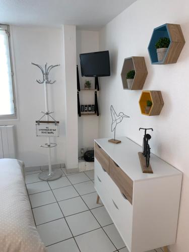 a white bedroom with a dresser and a tv at Studio Porte du Croux in Nevers