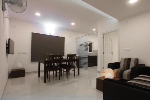 a living room with a table and chairs and a tv at Livi Suites - Premium 1 BHK Serviced Apartments in Bangalore