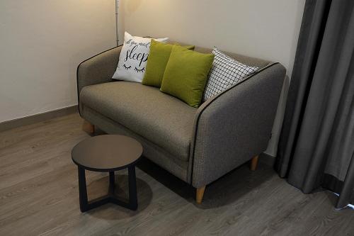 a couch with pillows and a table in a room at Siam Mansion - SHA in Hat Yai