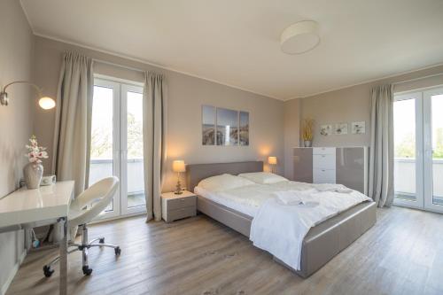- une chambre avec un lit, un bureau et des fenêtres dans l'établissement Penthouse im Dorf, à Sankt Peter-Ording