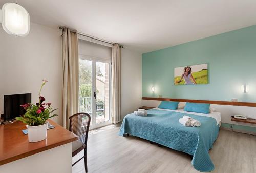 a bedroom with a bed and a desk and a window at I Giardini di Athena- Athena Resort in Scoglitti