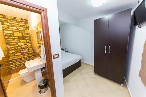 y baño con lavabo y pared de piedra. en Hotel Ajka, en Berat