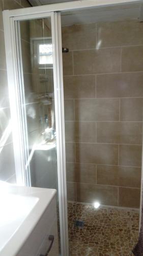 une douche avec une porte en verre à côté d'un lavabo dans l'établissement l'orchidée, à Talais