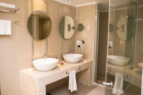 a bathroom with two sinks and two mirrors at Anemon Kent İskenderun Otel in İskenderun